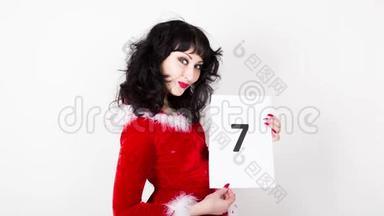 穿红色外套的年轻漂亮的女人拿着一张有数字的纸。 最后倒数